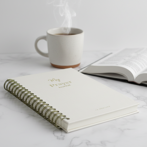 Open notebook with 'My Prayer Journal' on a marble surface next to a steaming mug.